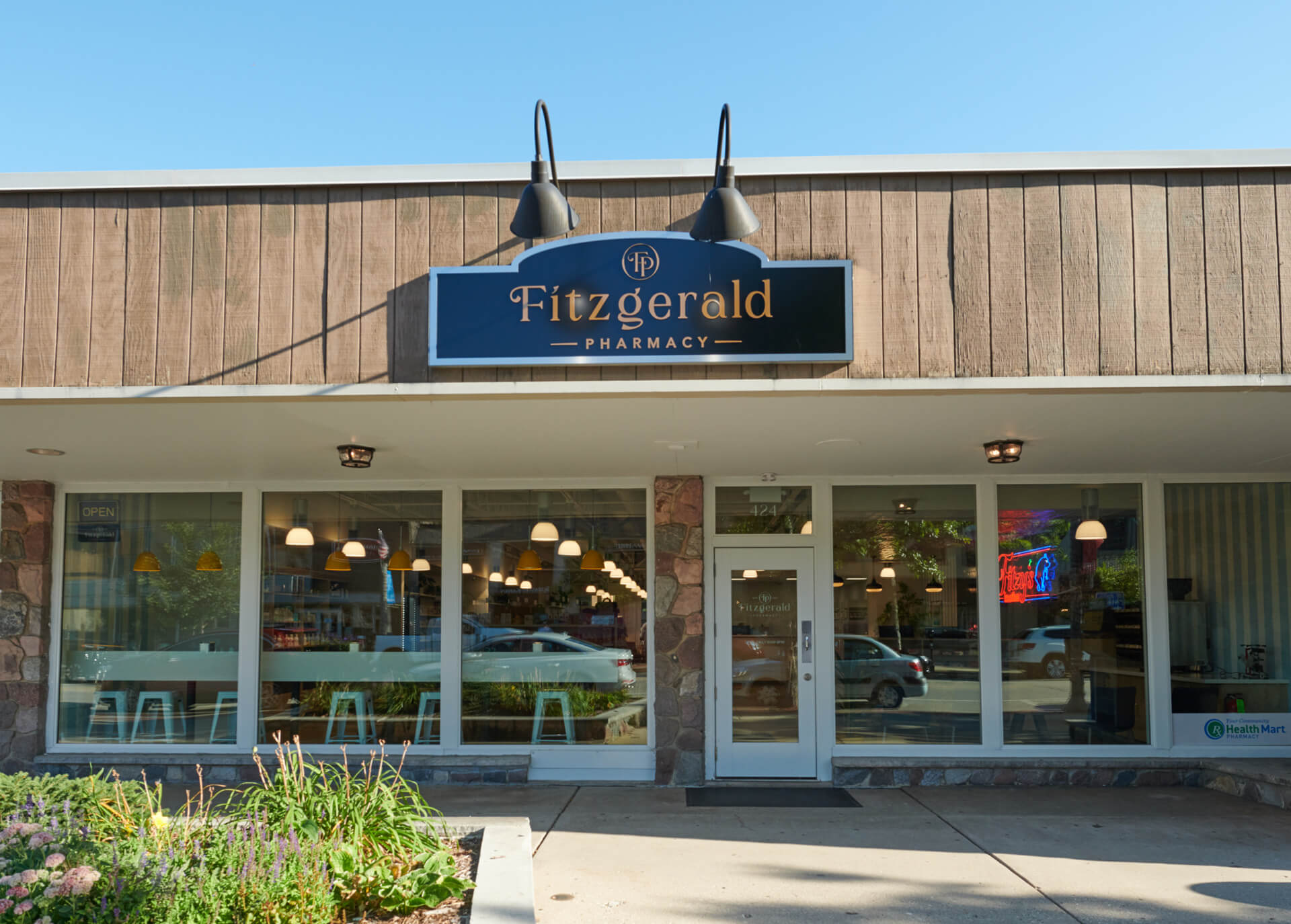 Fitzgerald's Whitefish Bay storefront with large big windows, and green bushy landscaping out front