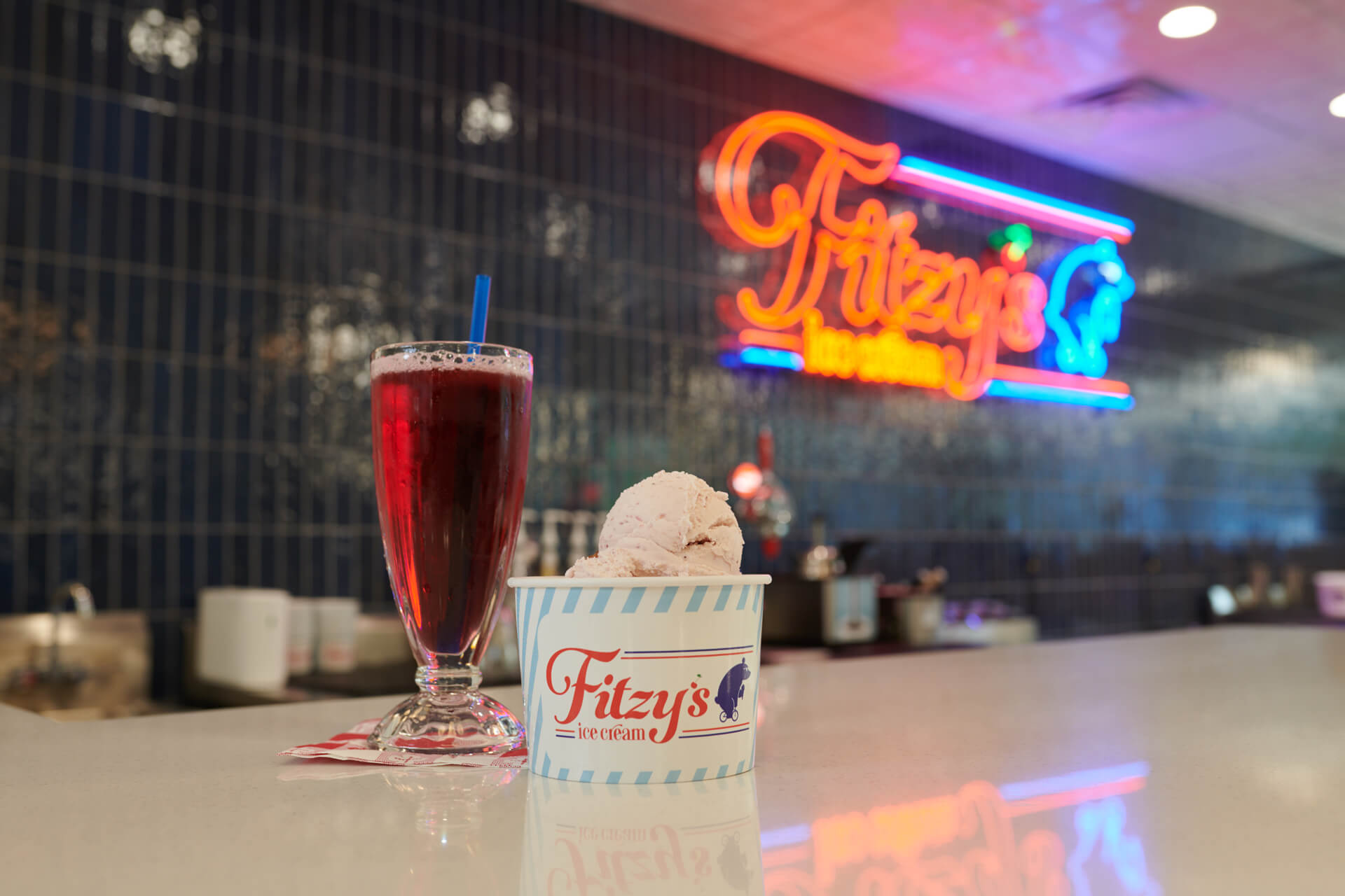 Fitzy's neon light counter, with large fountain drink and scoop of ice cream in a Fitzy's cup